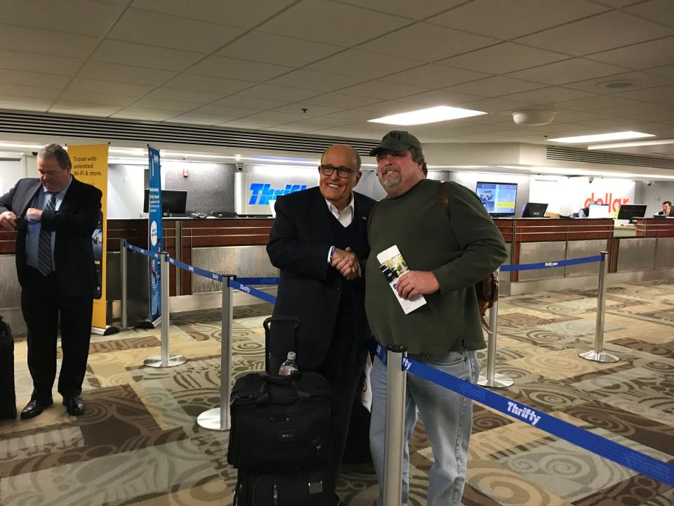Rudy Giuliani poses for a photo with a traveler at Nashville International Airport Nov. 25, 2019.
