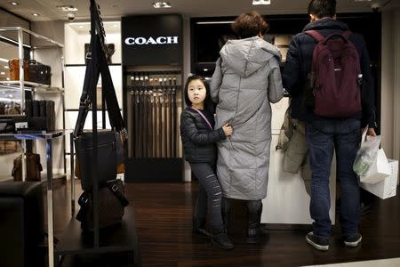 A Chinese girl holds on to her mother paying a bill at a Lotte department store in central Seoul, South Korea, February 2, 2016. REUTERS/Kim Hong-Ji