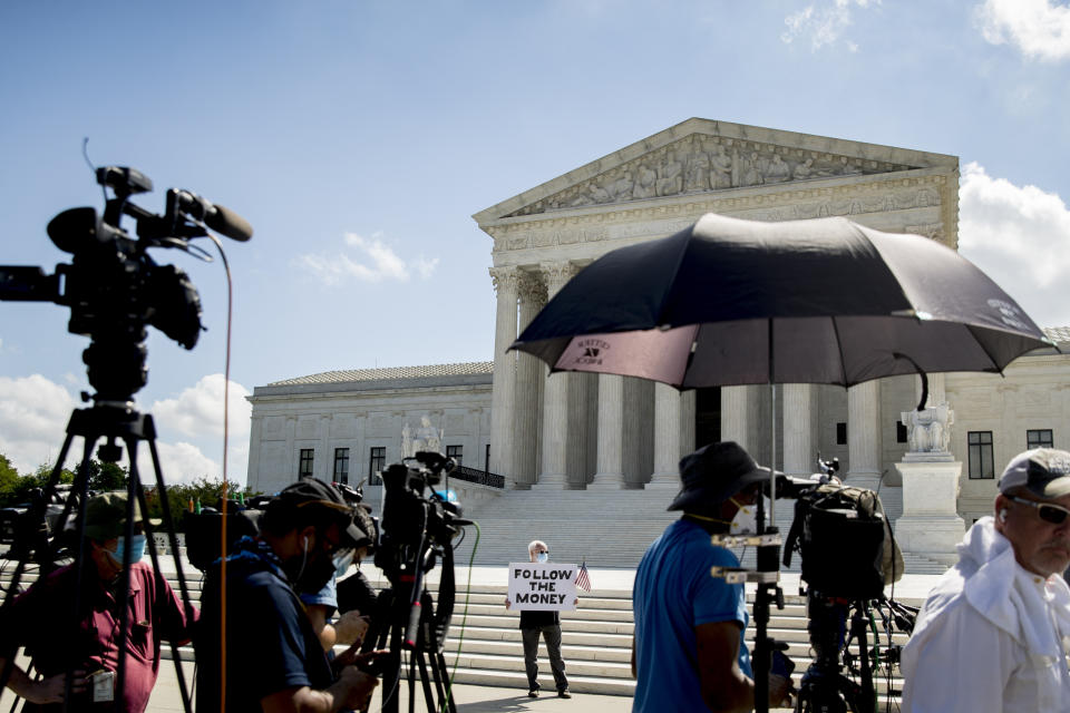 Bill Christeson holds up a sign that reads "Follow the Money" outside the Supreme Court, Thursday, July 9, 2020, in Washington. The Supreme Court ruled Thursday that the Manhattan district attorney can obtain Trump tax returns while not allowing Congress to get Trump tax and financial records, for now, returning the case to lower courts. (AP Photo/Andrew Harnik)