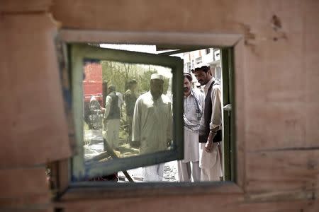 Afghan men look at a damaged kiosk at the site of a suicide attack in Kabul, Afghanistan July 7, 2015. REUTERS/Ahmad Masood