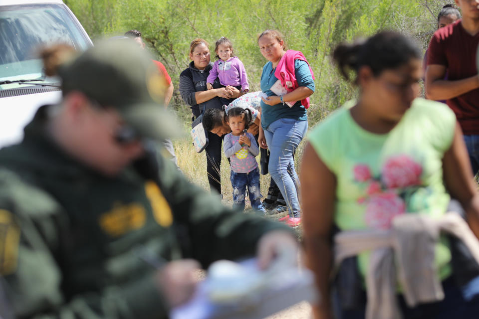 <p>Central American asylum seekers wait as U.S. Border Patrol agents take them into custody on June 12, 2018 near McAllen, Texas. The families were then sent to a U.S. Customs and Border Protection (CBP) processing center for possible separation. (Photo: John Moore/Getty Images) </p>