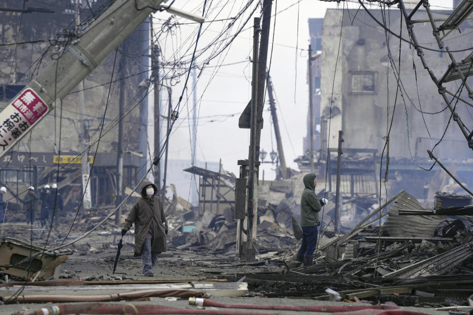 People walk through the damaged marketplace burned by fire after earthquake in Wajima, Ishikawa prefecture, Japan Tuesday, Jan. 2, 2024. (Kyodo News via AP)