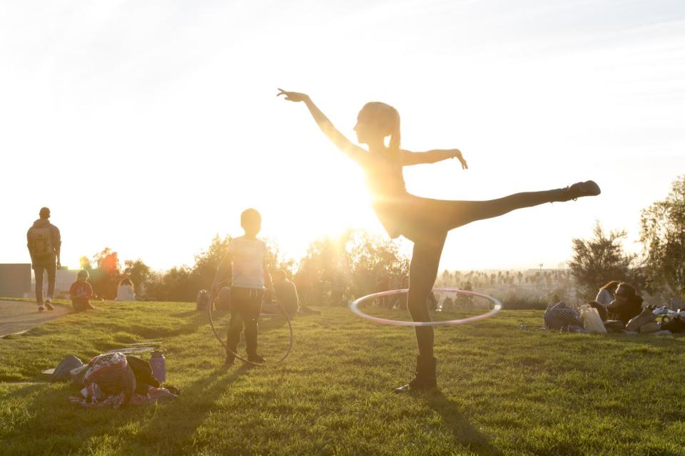 Kimberly Hamilton hula hoops at Barnsdall Art Park, silhouetted by the late-afternoon sun.