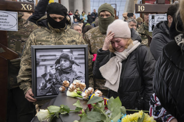 People pay last respect at a coffin of Maksym Mykhailov, 32, one of four Ukrainian servicemen who were part of a reconnaissance group and were killed on Dec. 25 in Russia as they performed a special task, during a farewell ceremony on the Independence square in Kyiv, Ukraine, Tuesday, March 7, 2023. Names of other servicemen are Maksym Mykhailov, 32, Yuri Horobets, 34, Taras Karpiuk, 36. (AP Photo/Efrem Lukatsky)