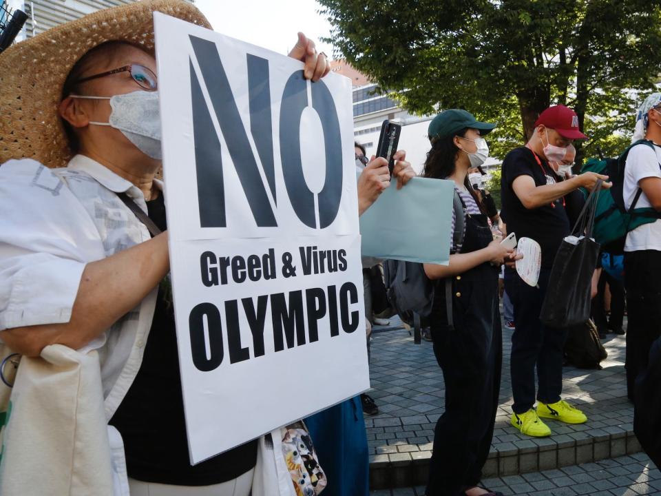 People hold signs to protest the Tokyo Olympics.