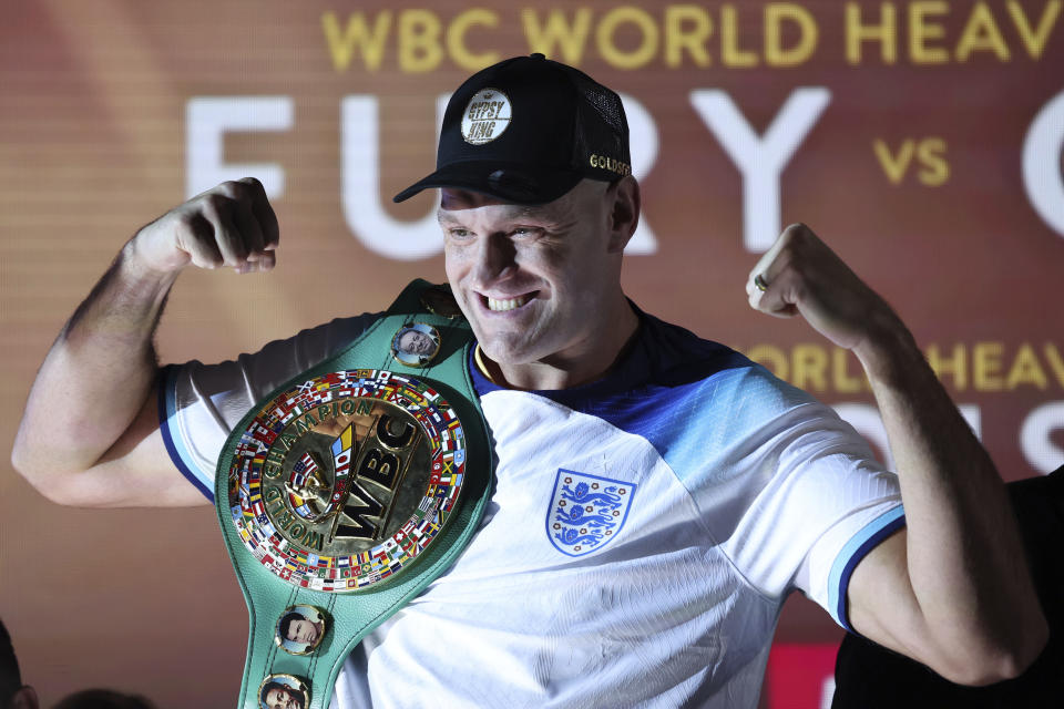 Boxer Tyson Fury the WBC heavyweight champion poses for the cameras with his championship belt and wearing an England soccer shirt after the official weigh-in, in London, Friday Dec. 2, 2022. Tyson Fury will fight against Derek Chisora on Dec. 3, at Tottenham Hotspur&#39;s stadium to defend his WBC heavyweight championship. (AP Photo/Ian Walton)