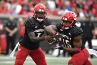 Louisville quarterback Malik Cunningham (3) hand the ball off to running back Jalen Mitchell (15) during the first half of an NCAA college football game in Louisville, Ky., Saturday, Oct. 23, 2021. (AP Photo/Timothy D. Easley)