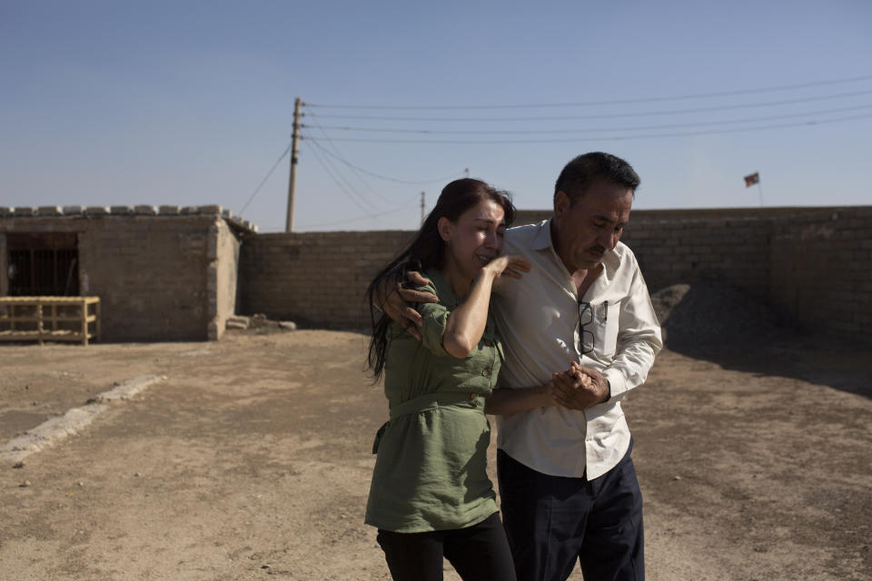 In this Aug. 31, 2019 photo, Layla Taloo is overcome with grief as her brother, Khalid, leads her away from the compound where she last saw her husband in 2014 after the family was captured by Islamic State militants, in Tal Afar, Iraq. Her family was taken to a village with nearly 2,000 other Yazidis forced to convert to Islam, before the men were taken away. Their bodies were never found, but they are believed to have been thrown into a nearby sinkhole. (AP Photo/Maya Alleruzzo)