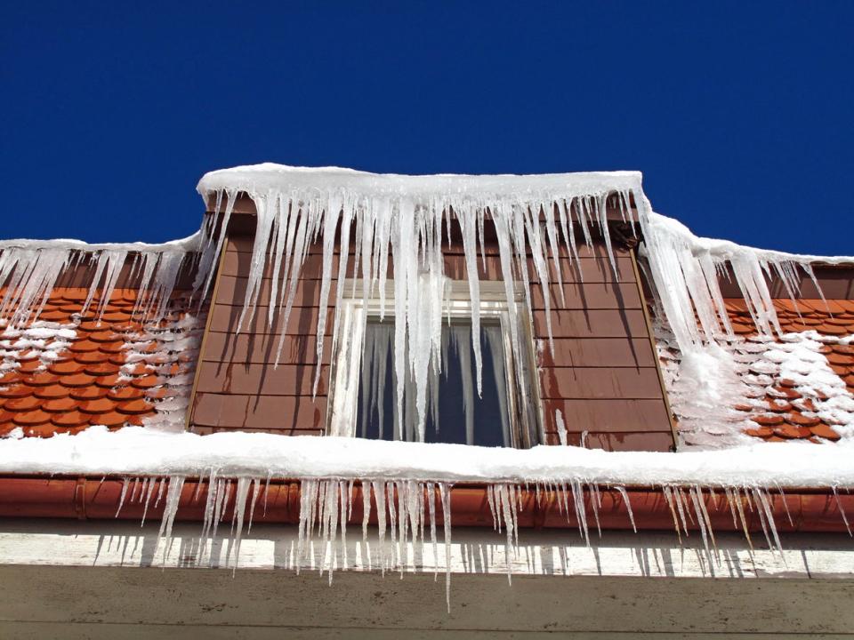 Icicles hang down from a red tile roof.