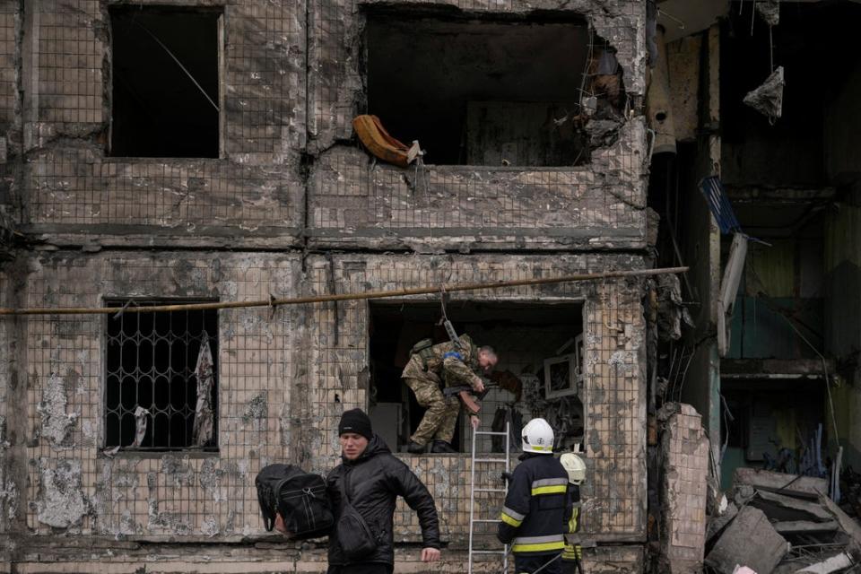 People retrieve belongings from an apartment in a block which was destroyed by an artillery strike in Kyiv, Ukraine on Monday, 14 March (AP)