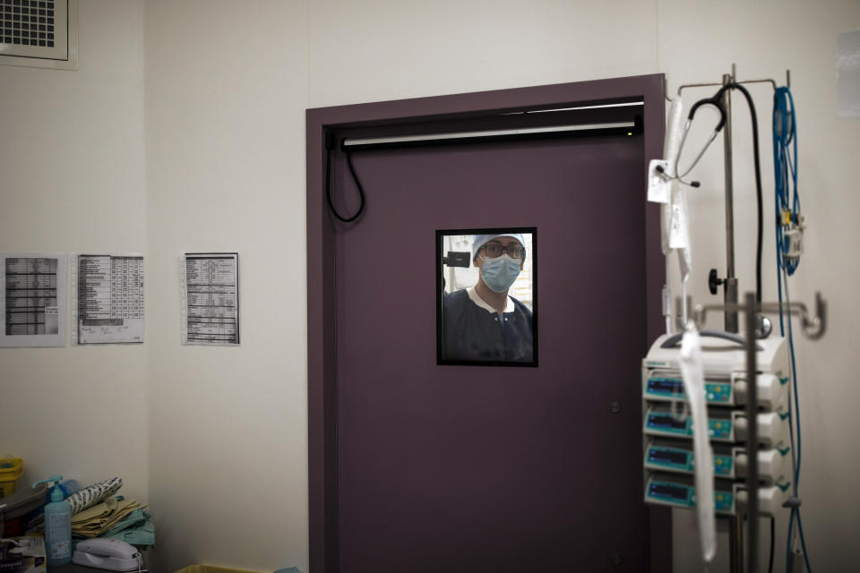 Nurse Guillaume Meuleman is seen through the window of an operating room at Bichat Hospital, AP-HP, in Paris, Thursday, April 22, 2021. France still had nearly 6,000 critically ill patients in ICUs this week as the government embarked on the perilous process of gingerly easing the country out of its latest lockdown, too prematurely for those on pandemic frontlines in hospitals. President Emmanuel Macron's decision to reopen elementary schools on Monday and allow people to move about more freely again in May, even though ICU numbers have remained stubbornly higher than at any point since the pandemic's catastrophic first wave, marks another shift in multiple European capitals away from prioritizing hospitals. In France, Greece and elsewhere, the cursor is moving back toward other economic, social and educational imperatives. (AP Photo/Lewis Joly)