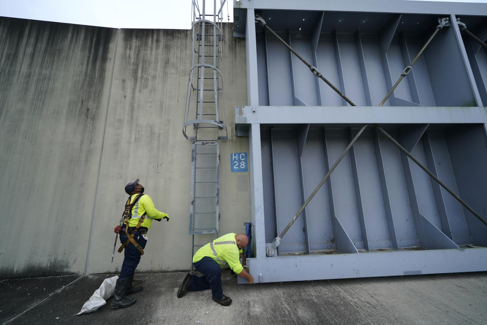 Workers for the Southeast Louisiana Flood Protection Authority - West close floodgates in Harvey, La., just outside New Orleans, Monday, Aug. 24, 2020, in advance of Tropical Storm Marco, expected to come near the Southern Louisiana coast. (AP Photo/Gerald Herbert)