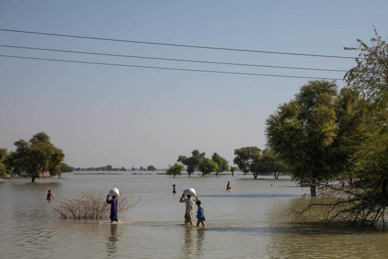 People walk through floodwater on October 18, 2022 in Johi, Pakistan. Nearly one-third of Pakistan was deeply affected by flooding which hit the country in 2022.