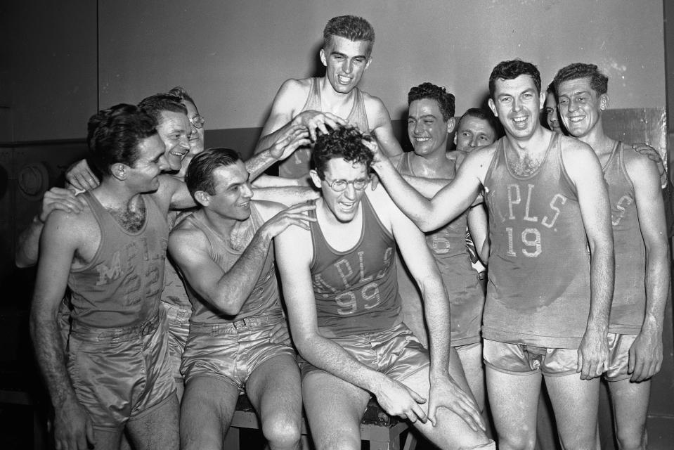 FILE - In this Feb. 22, 1949, file photo, Minneapolis Lakers George Mikan (99) gets his hair messed up by teammates in New York's Madison Square Garden dressing room. Front row, left to right: Don Forman, Tony Jaros, Mikan, and Jack Swan. Back row, left to right: Herman Schaefer, Whitey Kachan, Arnold Ferrin, John Jorgensen, Don Carlson, Coach John Kundla and Earl Gardner. (AP Photo/John Rooney, File)