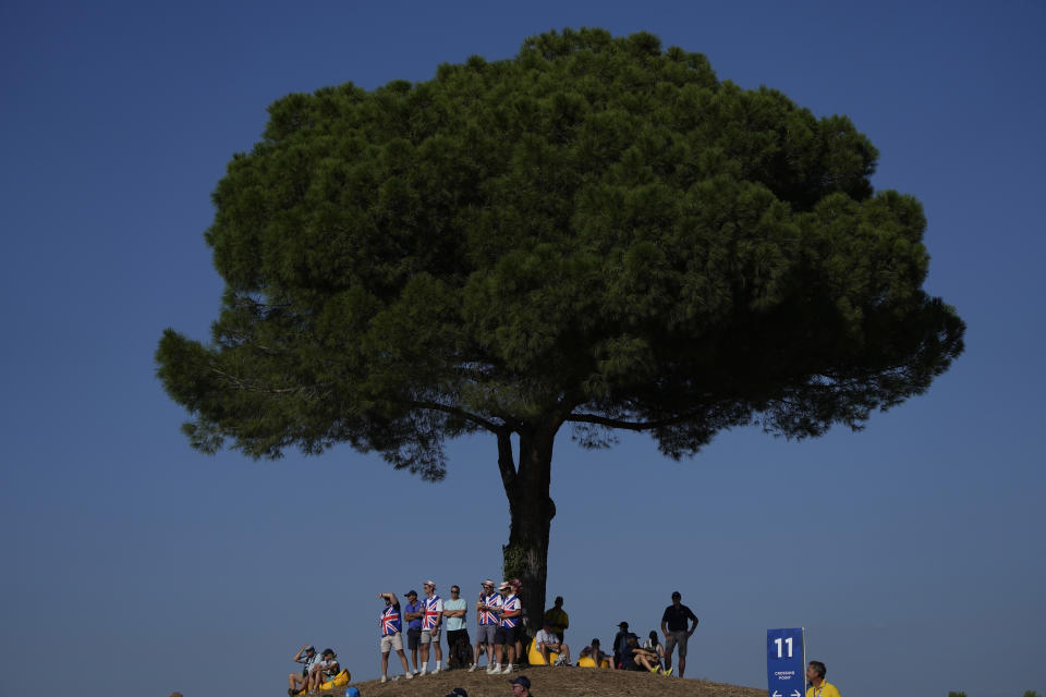 Golf fans seek the shade of a tree on the 11th fairway during the afternoon Fourballs matches at the Ryder Cup golf tournament at the Marco Simone Golf Club in Guidonia Montecelio, Italy, Friday, Sept. 29, 2023. (AP Photo/Alessandra Tarantino)