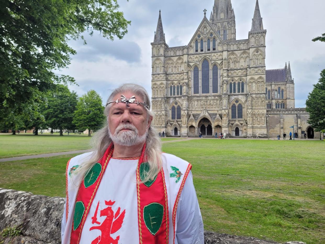 Druid dressed in traditional robe standing outside the entrance of Salisbury Cathedral