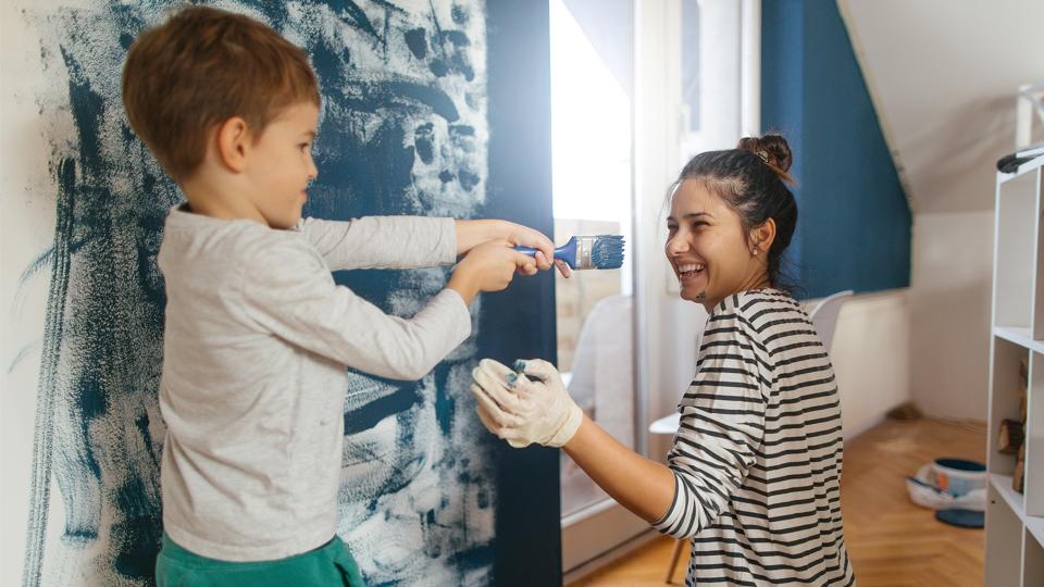 Mother and son working together on repainting a wall in their living room.