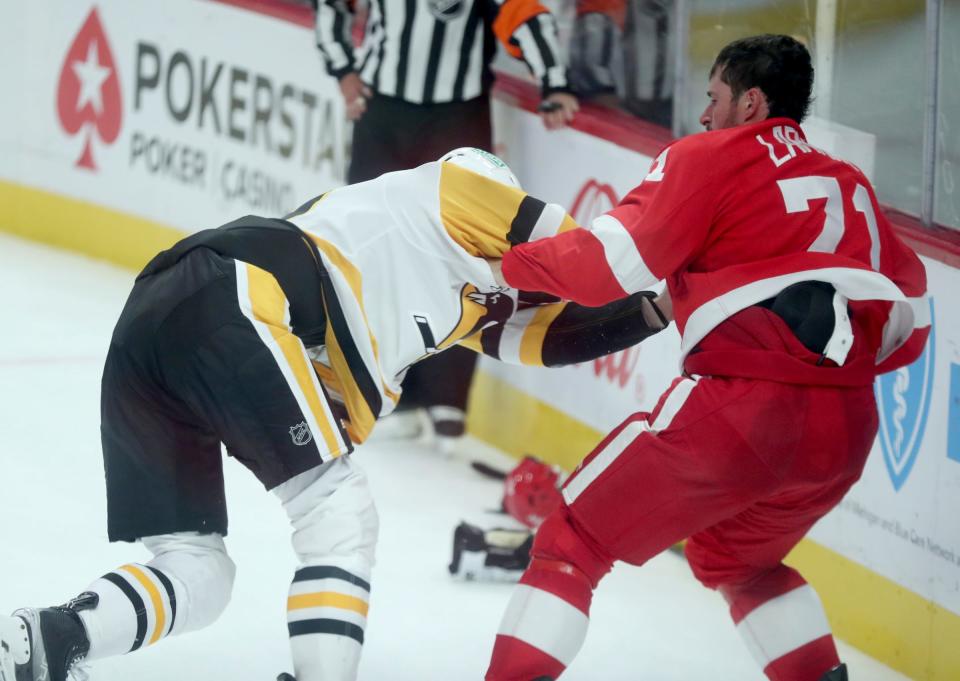 Red Wings center Dylan Larkin takes a swing against Penguins defenseman Marcus Pettersson during the second period of the Wings' 6-3 win on Wednesday, Oct. 18 2023, at Little Caesars Arena.