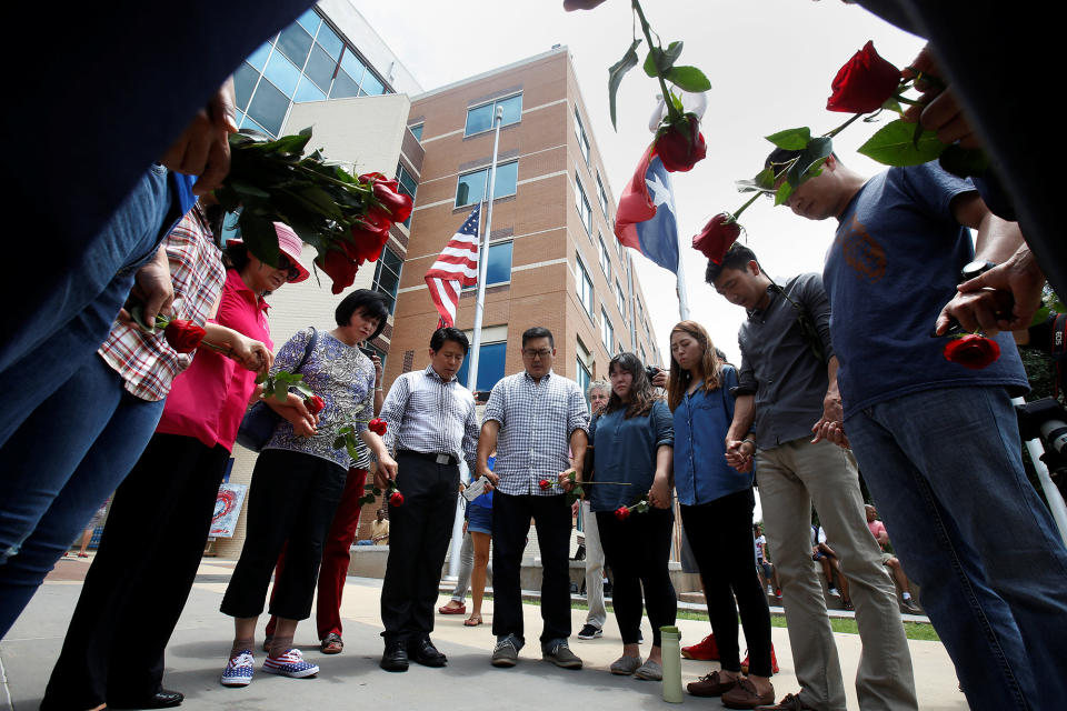 People hold hands as they sing and pray at a makeshift memorial at Dallas Police Headquarters