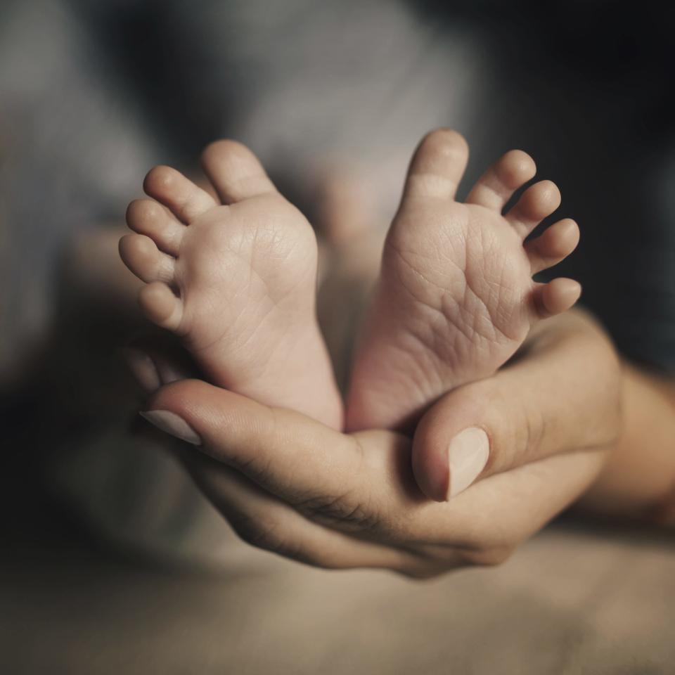 A mother holds the feet of a newborn baby [Via MerlinFTP Drop]