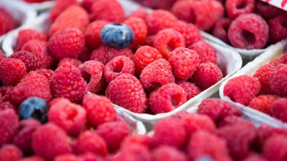 blueberries and raspberries seen displayed on the shelves of