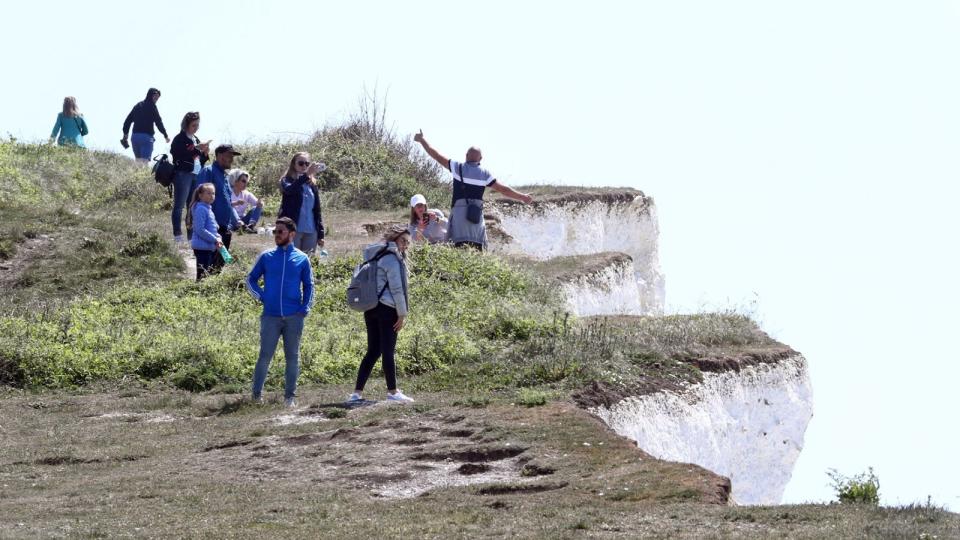 A man poses for a picture on the edge of dangerous cliffs