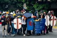 Venezuelan opposition activists protect themselves against water cannons during clashes with police, in Caracas, on May 1, 2017