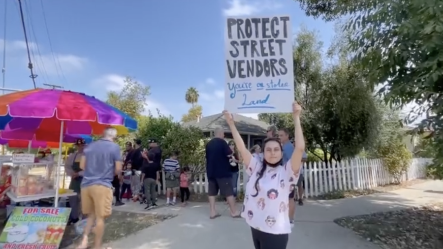 A woman holds up a sign in support of street vendors in Woodland Hills on Aug. 21, 2022. A rally was held in the same spot where a vendor was attacked by an ax-wielding man (KTLA)