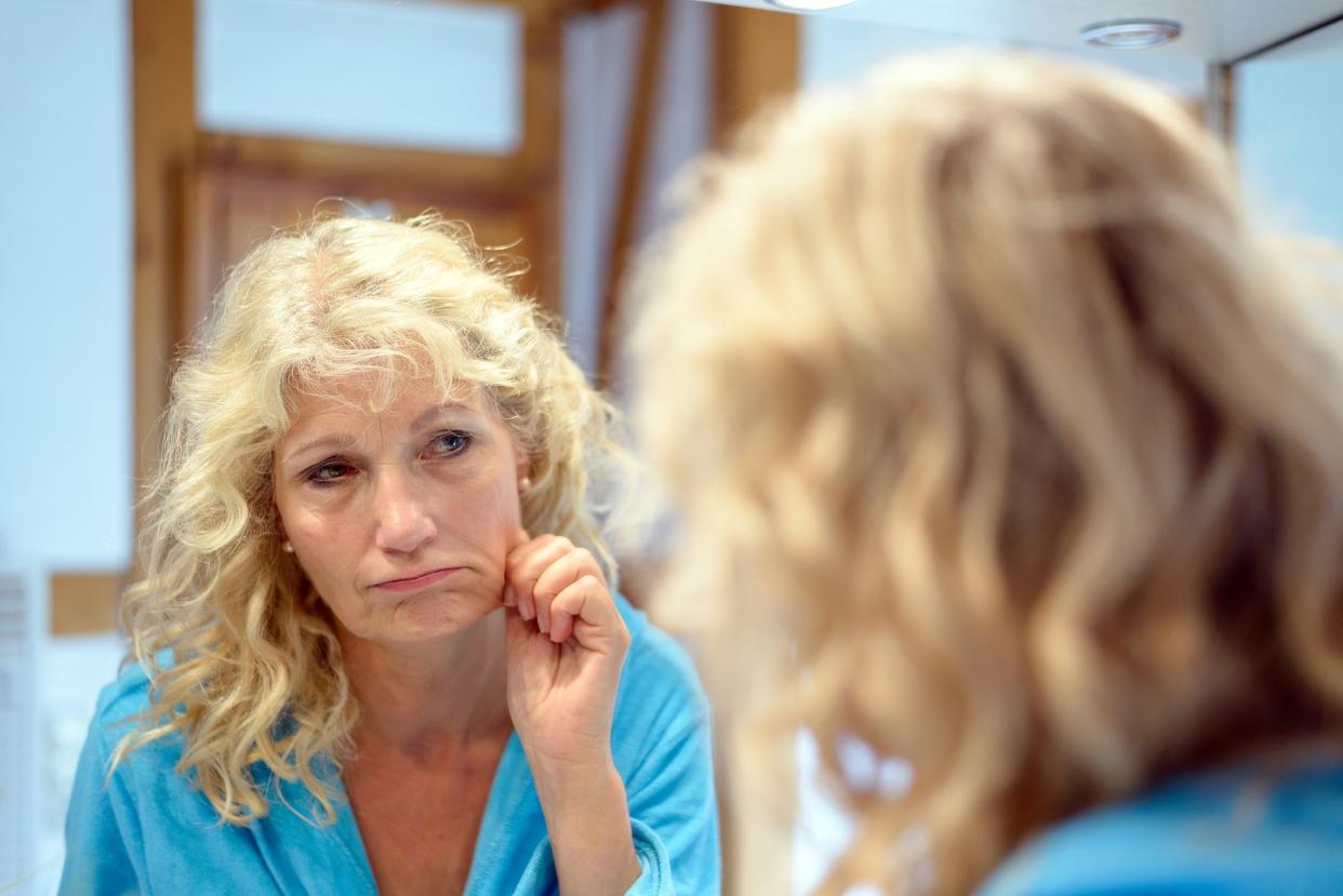 senior blond woman checking her aging skin