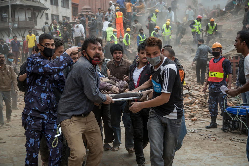 Emergency rescue workers carry a victim on a stretcher after Dharahara Tower collapsed on April 25, 2015, in Kathmandu, Nepal. (Omar Havana/Getty Images)