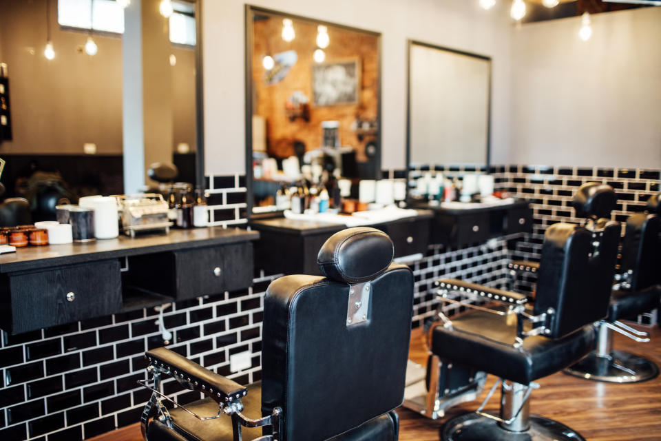 Empty black chairs and mirrors in barber shop. Interior of illuminated hair salon.