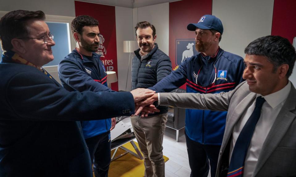 in a scene from ted lasso, higgins, roy, ted, beard and nate gather in the coaches' room for a pre match ritual