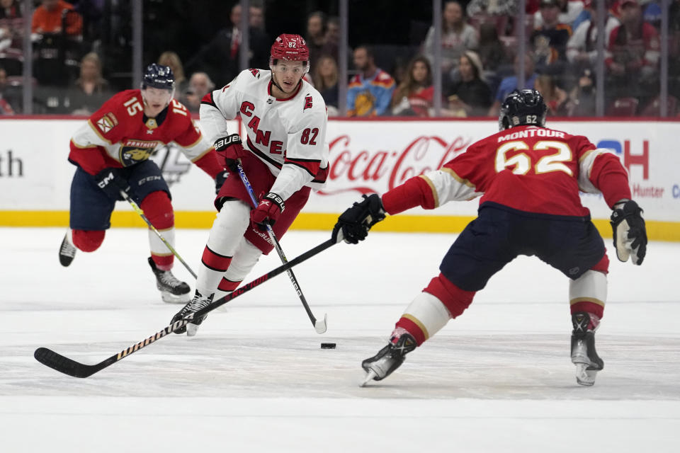 Carolina Hurricanes center Jesperi Kotkaniemi (82) skates with the puck as Florida Panthers defenseman Brandon Montour (62) defends during the first period of an NHL hockey game, Thursday, April 13, 2023, in Sunrise, Fla. (AP Photo/Lynne Sladky)