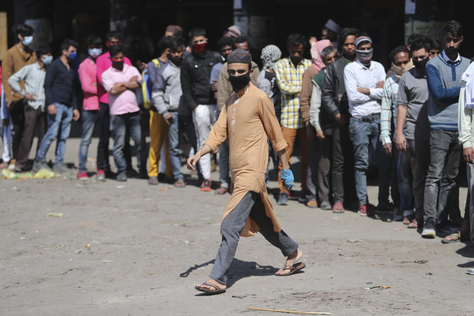 Indian passengers who got stranded at a bus terminal line up for free food being distributed by shop keepers during a day long lockdown amid growing concerns of coronavirus in Jammu, India, Sunday, March 22, 2020. India is observing a 14-hour “people's curfew” called by Prime Minister Narendra Modi in order to stem the rising coronavirus caseload in the country of 1.3 billion. For most people, the new coronavirus causes only mild or moderate symptoms. For some it can cause more severe illness. (AP Photo/Channi Anand)