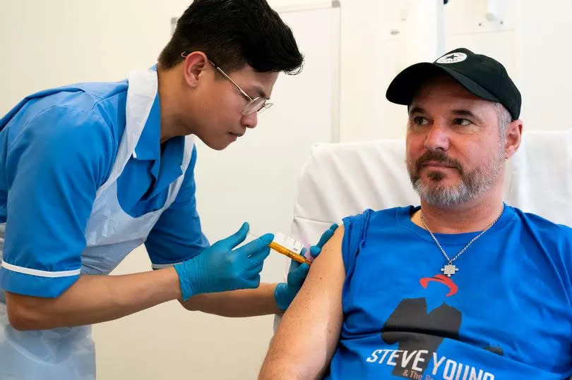 Nurse Christian Medina administers patient Steve Young with his first jab at the University College London Hospital