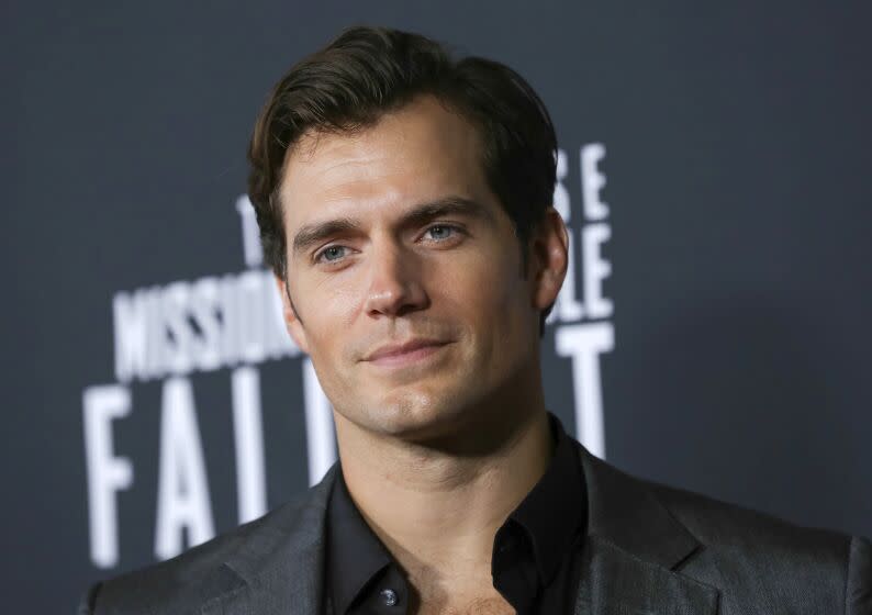 A attractive man in a suit jacket poses at a movie premiere