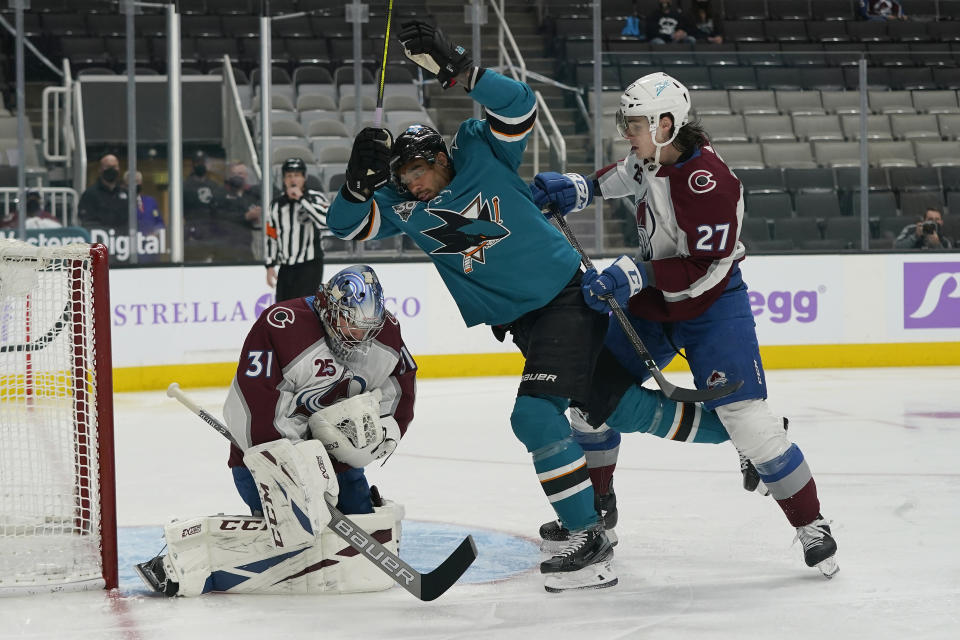 Colorado Avalanche goaltender Philipp Grubauer, left, grabs the puck in front of defenseman Ryan Graves (27) and San Jose Sharks left wing Evander Kane, middle, during the first period of an NHL hockey game in San Jose, Calif., Monday, May 3, 2021. (AP Photo/Jeff Chiu)