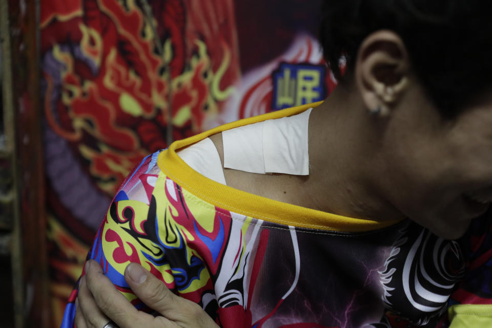 Therry Sicat, one of the managers of the Sicat Brothers Dragon and Lion dance group, shows strips he placed on his shoulder to relieve pain as they rush to finish miniature lion heads at a creekside slum at Manila's Chinatown, Binondo Philippines on Feb. 3, 2021. The Dragon and Lion dancers won't be performing this year after the Manila city government banned the dragon dance, street parties, stage shows or any other similar activities during celebrations for Chinese New Year due to COVID-19 restrictions leaving several businesses without income as the country grapples to start vaccination this month. (AP Photo/Aaron Favila)
