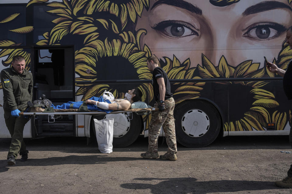 Volunteers from the Hospitallers paramedic organisation transport Oleksandr, an injured Ukrainian soldier, into the special medical bus during evacuation in Donetsk region, Ukraine, Wednesday, March 22, 2023. (AP Photo/Evgeniy Maloletka)