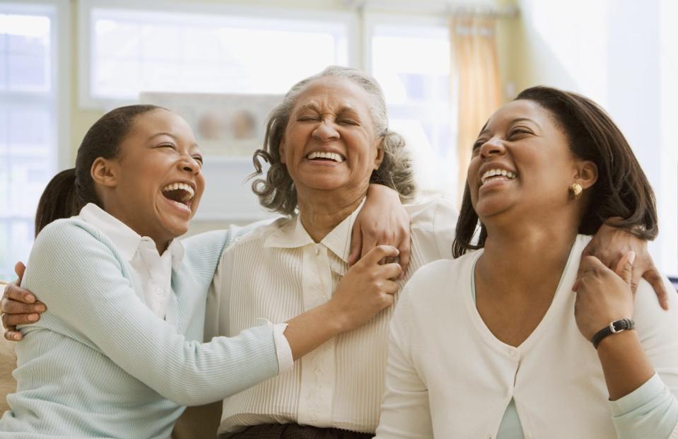 girl, older woman and middle-aged women smiling with their arms around each other