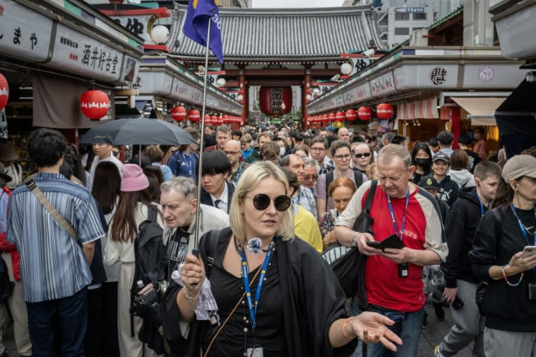 Una guía conduce a un grupo de turistas por una calle cercana al templo Sensoji de Tokio, en Japón, el 30 de abril de 2024 (Yuichi YAMAZAKI)