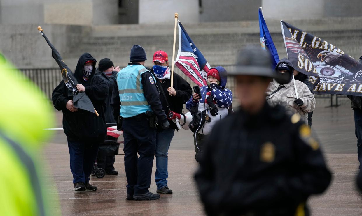 Officer Joshua Rhoads, a member of the Columbus police dialogue team, keeps distance between a group of far-right Proud Boys extremist group members and counter protesters who had gathered outside the Ohio Statehouse on the anniversary of the January 6 insurrection.