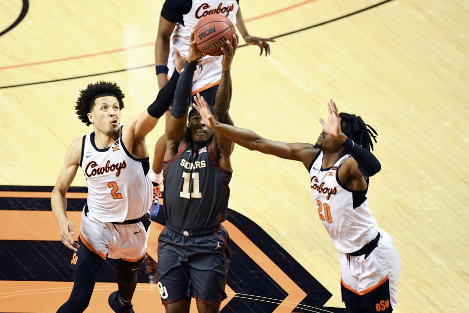 Oklahoma State guards Cade Cunningham (2) and Keylan Boone (20) attempt to block a shot by Oklahoma guard De'Vion Harmon (11) during an NCAA college basketball game Monday, March 1, 2021, in Stillwater, Okla. (AP Photo/Brody Schmidt)