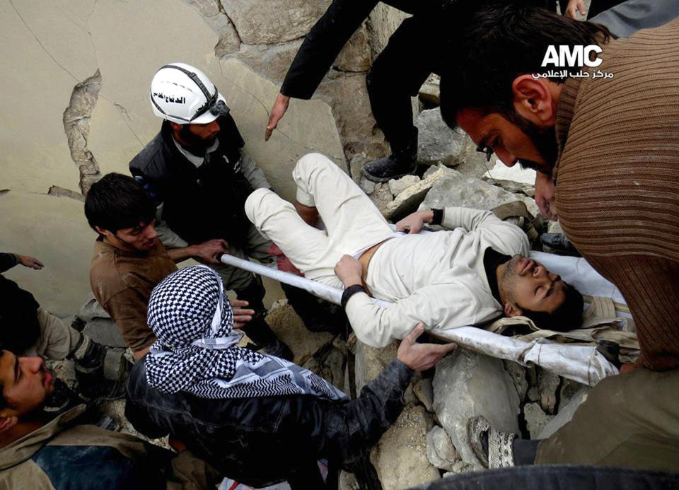 In this picture taken on on Thursday, Jan. 23, 2014, a citizen journalism image provided by Aleppo Media Center (AMC), an anti-Bashar Assad activist group which has been authenticated based on its contents and other AP reporting, Syrian residents and rescue workers carry an injured man from a building damaged, according to AMC, attacked by the Syrian forces airplanes in Aleppo, Syria. AMC said the attack was by the Syrian forces airplanes. Direct talks planned between President Bashar Assad's government and the Western-backed opposition hoping to overthrow him were scrapped Friday, and the two sides will meet a U.N. mediator in different rooms at different times. (AP Photo/Aleppo Media Center, AMC)