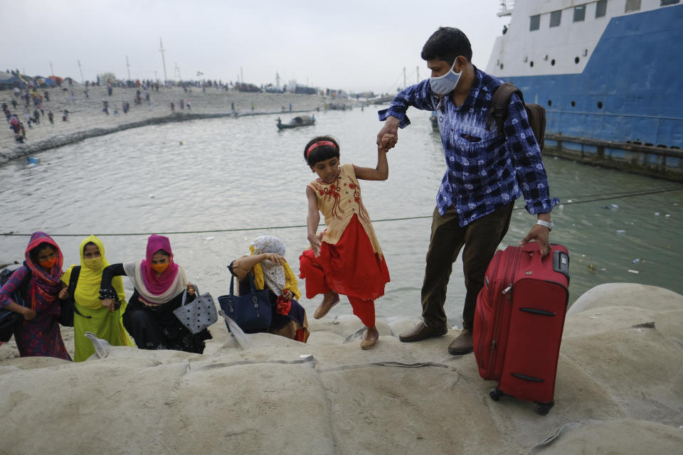 A man holds a child's hand as thousands of people leaving for their native places to celebrate Eid-al-Fitr rush to the Mawa ferry terminal ignoring risks of coronavirus infection in Munshiganj, Bangladesh, Thursday, May 13, 2021. (AP Photo/Mahmud Hossain Opu)