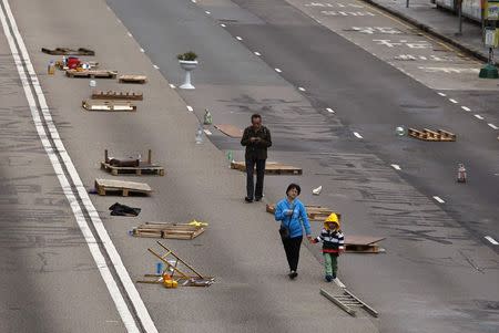 People walk past obstacles and barricades set up by pro-democracy protesters on a main road at the financial Central district in Hong Kong December 7, 2014. REUTERS/Bobby Yip