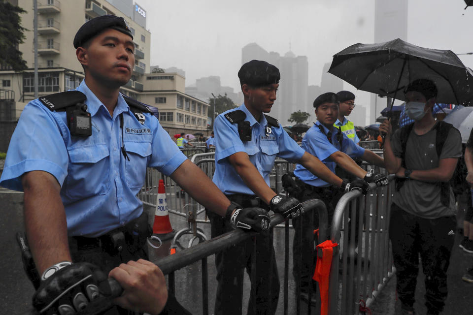 Policemen stand guard in the rain as protesters gather near the Legislative Council continuing protest against the unpopular extradition bill in Hong Kong, Monday, June 17, 2019. A member of Hong Kong's Executive Council says the city's leader plans to apologize again over her handling of a highly unpopular extradition bill. (AP Photo/Kin Cheung)