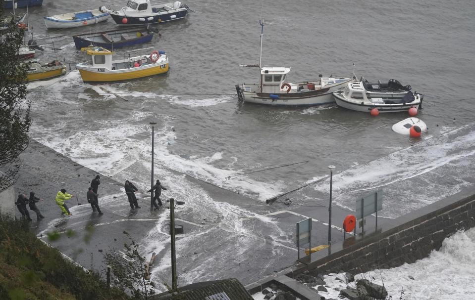 People hold a line to a boat at Stonehaven Harbour, in Scotland, Thursday, Oct. 19, 2023, as the UK braces for heavy wind and rain from Storm Babet. Hundreds of people are being evacuated from their homes and schools have closed in parts of Scotland, as much of northern Europe braces for stormy weather, heavy rain and gale-force winds from the east. (Andrew Milligan/PA via AP)
