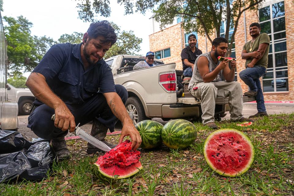 Junior Chavez, a painter for Dart Construction, slices watermelon for his co-workers while taking a break from painting window frames on the Scottish Rite Dormitory last month. Breaks won't be required under a state law going into effect soon.