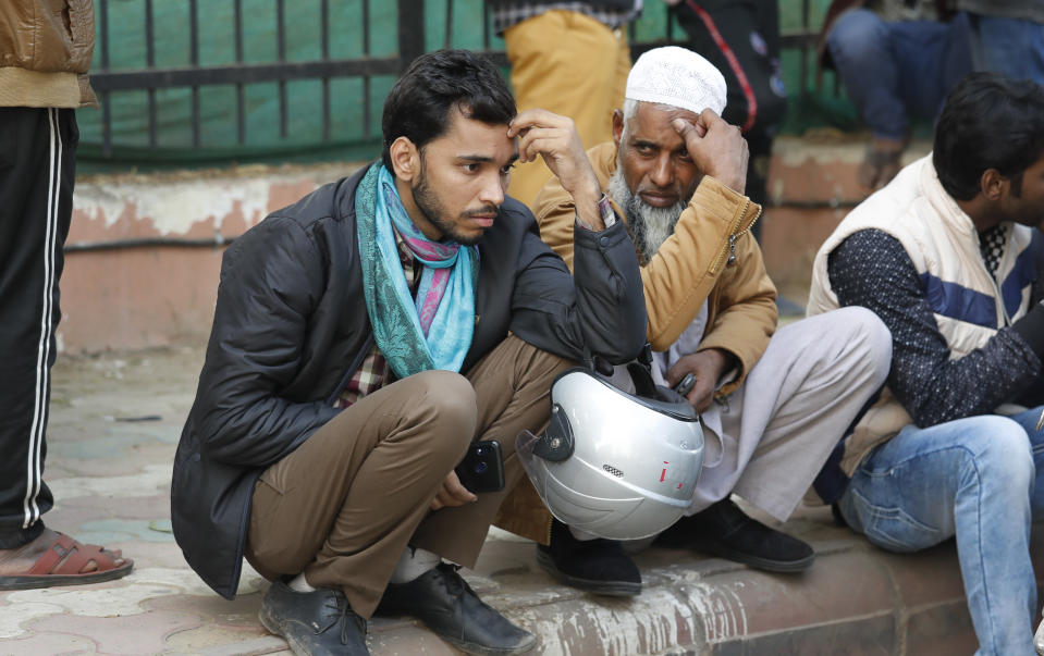 People wait to collect bodies of relatives who died in a fire in New Delhi, India, Sunday, Dec. 8, 2019. Dozens of people died on Sunday in a devastating fire at a building in a crowded grains market area in central New Delhi, police said. (AP Photo/Manish Swarup)